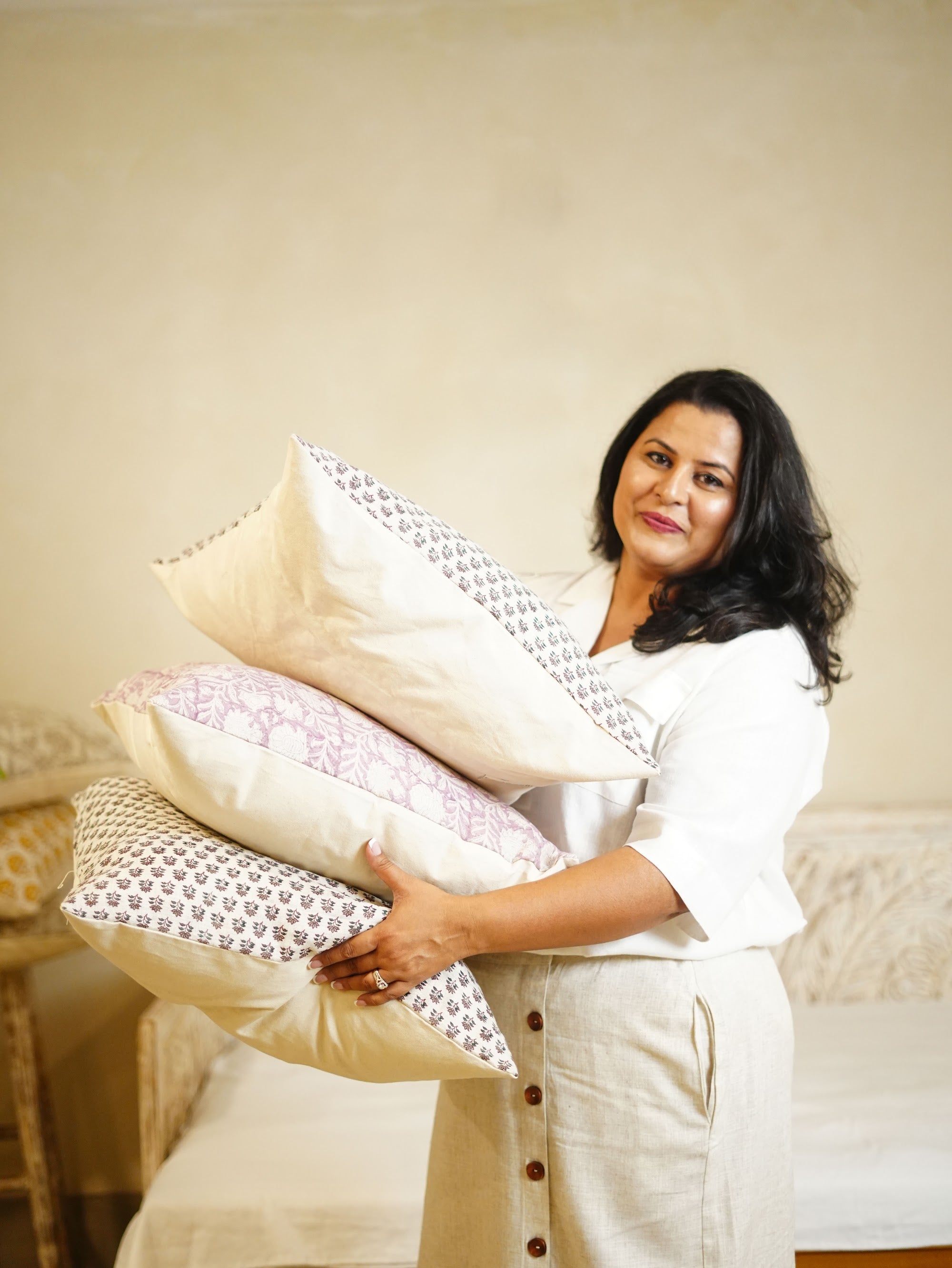 Navneet, founder of Hand & Earth, holding block-printed cushions